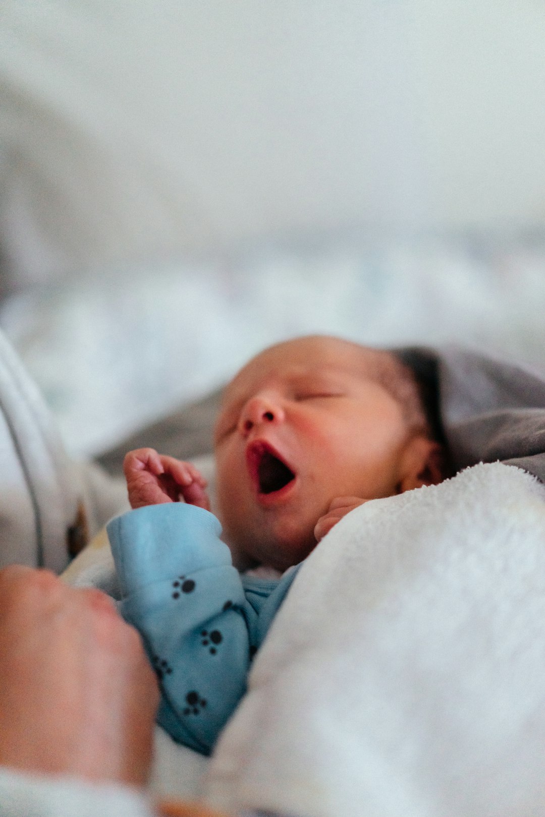 baby-in-white-and-blue-onesie-lying-on-bed-sgowvrfpavw