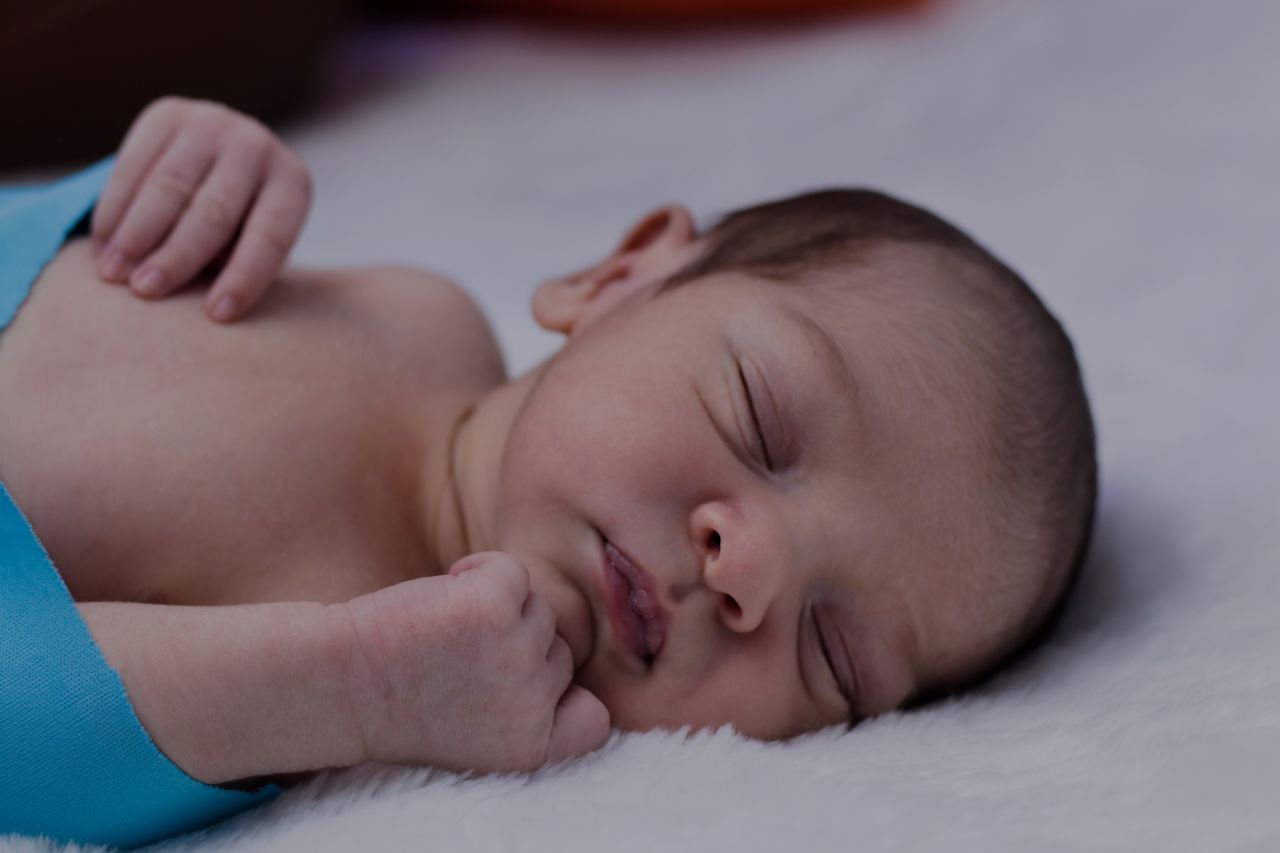 A serene portrait of a sleeping newborn baby wrapped in a soft blue blanket.